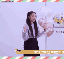a woman giving a thumbs up in front of balloons and a sign that says sec on it