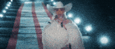 a woman wearing a cowboy hat and a fur coat sings into a microphone