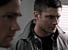 two men are standing next to each other and one of them is wearing a jacket .