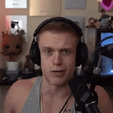 a man wearing headphones is standing in front of a microphone in a room .