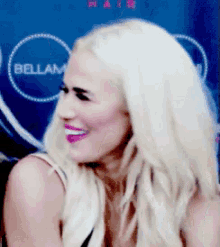 a woman is smiling in front of a sign that says bellam