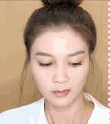 a close up of a woman 's face with a bun on her head .