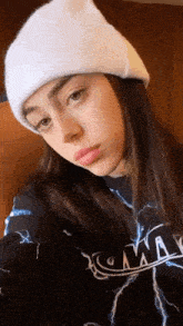 a young woman wearing a white beanie and a black shirt with lightning bolts on it