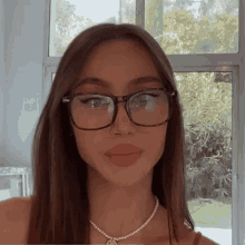 the woman is wearing glasses and a pearl necklace