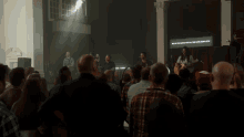 a group of people sitting in front of a stage with a sign that says " why you are the only one who step "