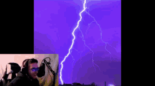 a man wearing headphones is watching a lightning strike