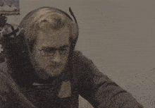a man wearing headphones and glasses is making a gesture