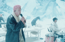 a man singing into a microphone in front of a snowy background