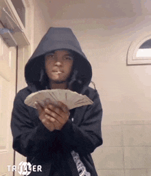 a person in a hoodie holding a bunch of money