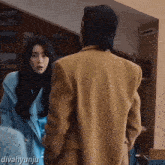 a woman in a blue coat stands next to a man in a brown coat with divahyunju written on the bottom right
