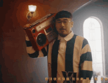 a man in a striped shirt is holding a boombox over his shoulder