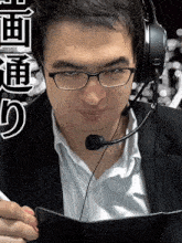 a man wearing glasses and a microphone looks at a notebook