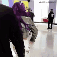 a man in a black jacket with a skull on it stands next to a woman with purple hair ..