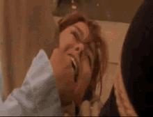 a woman is laying on the floor with her eyes closed and a man is holding her .