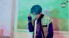 a man with blue hair is standing in front of a blackboard and a sign that says bts bomb .
