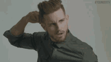 a man with a beard is scratching his head while wearing a black shirt .