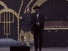 a man in a suit and tie is dancing on a stage while another man watches .