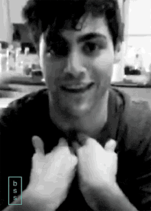 a black and white photo of a man giving a thumbs up with the letters bs on the bottom right