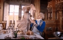 a man and woman are dancing at a table with candles and a bottle of champagne