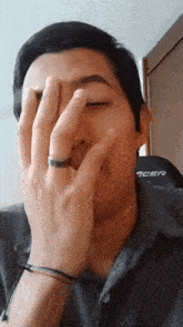 a man covering his face with his hands while wearing an acer chair in the background