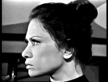 a black and white photo of a woman with a bun on her head .
