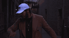 a man wearing a hat and a trench coat is laying on the ground in an alleyway .