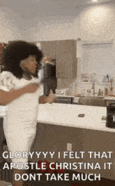 a woman in a white dress is dancing in a kitchen while holding a cup of coffee .