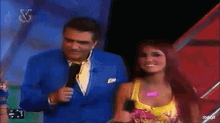 a man in a blue suit stands next to a woman in a yellow top