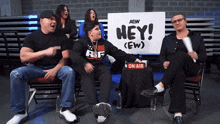 a group of people sitting in front of a sign that says hey ( ew )