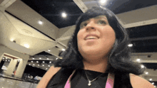 a woman with black hair and a necklace smiles