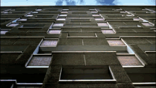 looking up at a building with many windows and a blue sky in the background