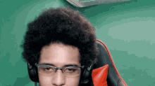 a man wearing glasses and headphones sits in a chair
