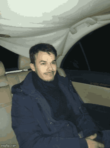 a man is sitting in the back seat of a car with imgflip.com written on the bottom right