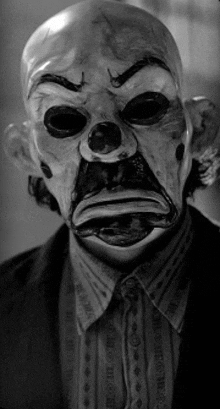 a black and white photo of a clown mask on a man 's face .