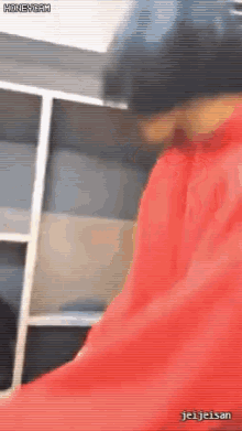 a man in a red hoodie is standing in front of a shelf