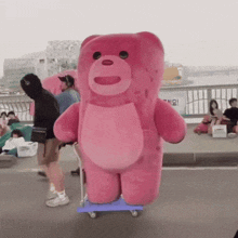 a large pink teddy bear is being pushed on a blue cart