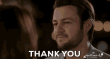 a man with a beard is giving a thank you sign to a woman
