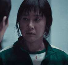 a woman wearing a green jacket looks at a man