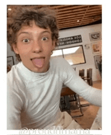 a young man is sticking his tongue out in front of a sign that says london