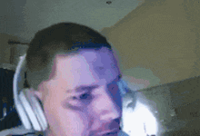a man wearing headphones looks at the camera with a purple background