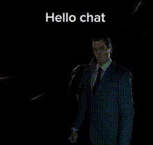 a man in a suit and tie is talking into a microphone and the words hello chat are above him