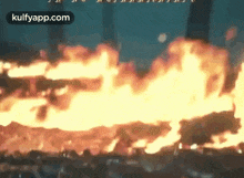 a large fire is burning in a dark room with a lot of flames coming out of it .