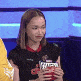 a woman in a black top is holding a candy bar that says gwen