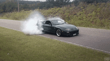 a car is driving down a road with smoke coming out of the tire