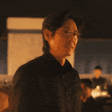 a man wearing glasses and a black shirt is pointing up