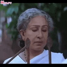 a woman with gray hair is holding a pair of wooden spoons in front of her face .