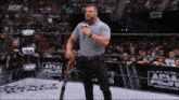a wrestler is holding a microphone in front of a aew wrestling ring