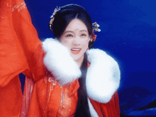 a woman in a red coat with a white fur collar is smiling