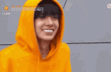 a young man wearing a yellow hoodie is smiling and making a funny face