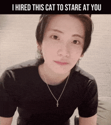 a woman wearing a black shirt and a necklace with the words i hired this cat to stare at you below her